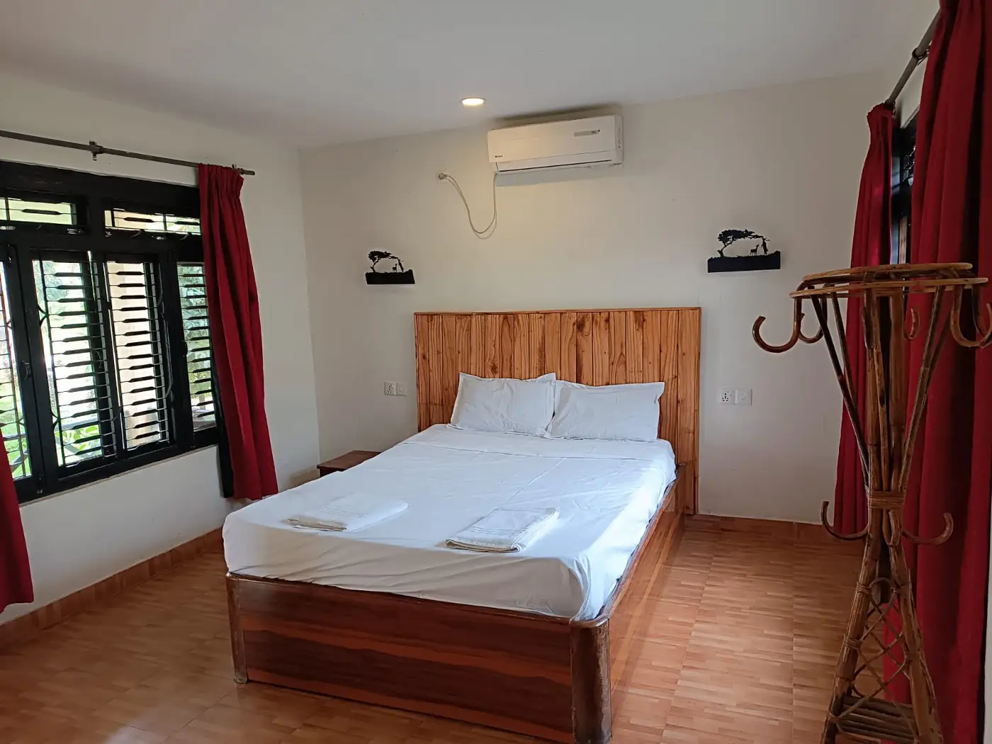 Superior double room with wooden bed and red curtains